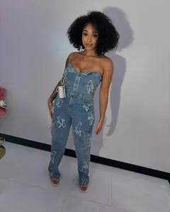 Detail of blue denim tube top jumpsuit featuring white cross embroidery motifs