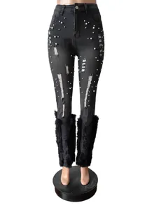 Detailed view of distressed black jeans with white pearl accents and faux fur hem.