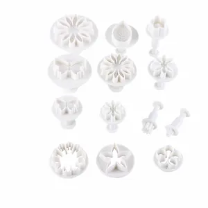 Detail view of various white plastic fondant cutters including flowers and butterflies