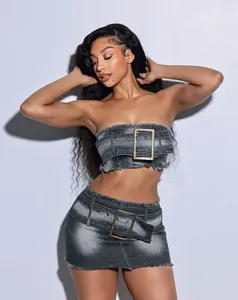 Woman wearing a two-piece washed denim set with tube top and mini skirt with oversized buckles