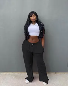 Detail view of black high-waisted wide-leg trousers styled with a white crop top