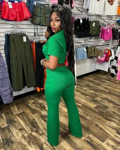 Full view of model wearing a green short-sleeved denim set with flared pants in a boutique