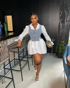 Model wearing white flare sleeve shirt dress with denim corset vest in a bar setting