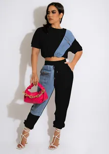 Fashion model wearing a black denim patchwork tracksuit set with pink handbag detail