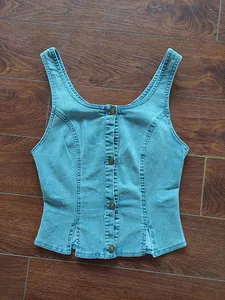 Close-up detail showing the light blue denim vest with front buttons and side slits