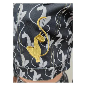 Detalle de bordado de gato amarillo y patrones blancos en un elegante conjunto negro