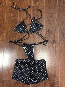 Vista dettagliata del set bikini a tre pezzi a pois bianchi e neri su fondo di legno