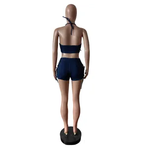 Vista trasera de un conjunto vaquero azul oscuro con top sin espalda y shorts con cordones.