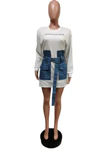 Detailed view of white long sleeve dress with blue denim patchwork and adjustable belt