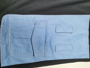 Close-up detail of light blue denim dress showing pocket construction and stitching