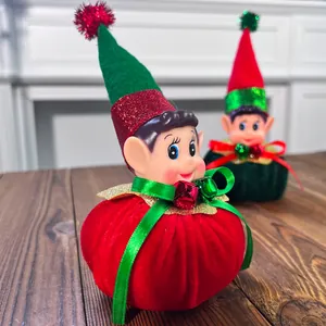 Close-up of adorable Christmas elf figurine with red velvet base and green glitter hat