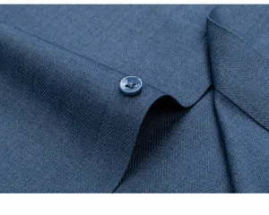 Gros plan du tissu de chemise bleu marine avec motif à chevrons et bouton en résine.
