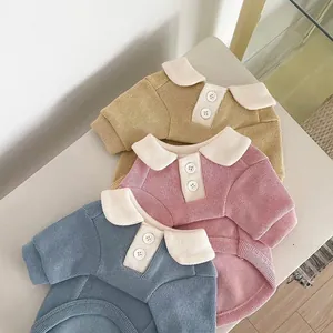 Primer plano de suéteres acanalados para mascotas en rosa, azul y amarillo con cuello