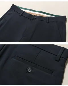 Close-up details of men's navy dress pants waist and back pocket with button closures.