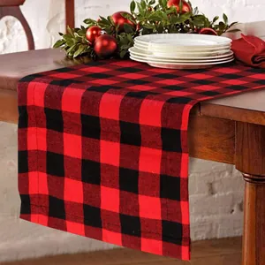 Detail view of red and black buffalo plaid Christmas table runner on a wooden table.