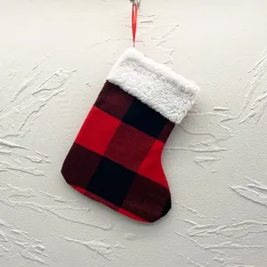 Red and black buffalo plaid Christmas stocking with white faux fur trim against a wall