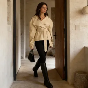 Stylish cream belted long sleeve jacket for women in a rustic interior setting.
