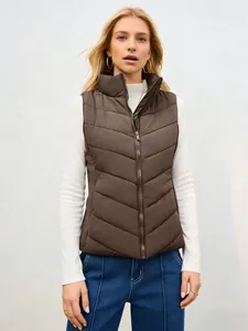 Modelo con chaleco acolchado marrón de cuello alto, suéter blanco y pantalón azul