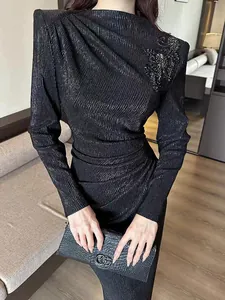 Detail showing the black textured fabric and elegant sequined floral shoulder design.