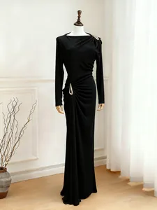 Elegant black long-sleeved maxi dress with artistic waist pleats and metal detail