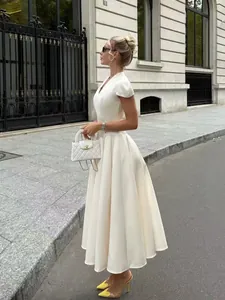 Side view of an elegant white V-neck dress with petal sleeves in a luxury street setting.