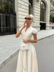 Elegant white V-neck puff-sleeve petal dress shown in a luxury outdoor street setting