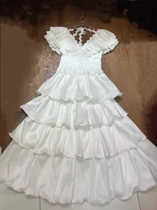 Detailed view of an elegant white tiered ruffle evening gown with a pleated hemline