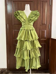 Elegant green tiered ruffled evening gown with pleated layers on display mannequin.