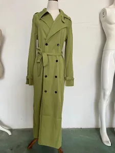 Vista detallada de una gabardina larga cruzada verde oliva en un maniquí de costura.