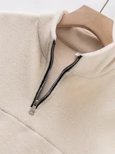 Close-up detail of beige fleece half-zip sweatshirt with stand collar and metal zipper