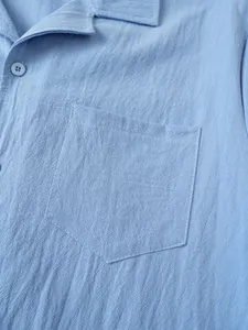Detalle de cerca del bolsillo del pecho y la textura de la tela de camisa azul de lino.