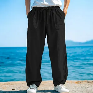 Men's loose black beach pants with drawstring waist and pockets in a seaside setting