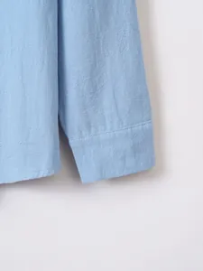 Close-up of light blue cotton linen shirt cuff showing fabric texture and stitching