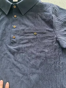 Detailed view of a blue cotton linen polo shirt with textured fabric and wooden buttons