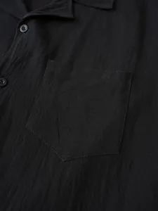 Close-up detail of a black men's cotton linen shirt showing fabric texture and chest pocket