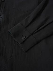 Detailed close-up showing the sleeve cuff and button of a black cotton linen shirt