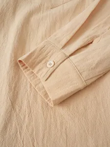 Primer plano de la textura del lino y detalle del botón en el puño de camisa beige para hombre