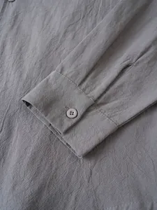 Primer plano del puño con botón y el tejido de algodón y lino de esta camisa gris informal