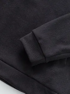 Detailed close-up showing the soft fleece texture and rib-knit cuff of a black men's sweatshirt