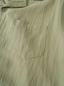 Close-up of olive green cotton linen fabric texture and chest pocket on men's casual shirt