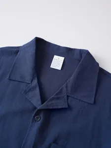 Primer plano del cuello de una camisa de lino azul marino con etiqueta de lavado.