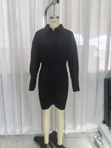 Elegante abito a camicia nero a maniche lunghe con gonna a pieghe su manichino