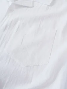 Detalle de cerca que muestra el bolsillo y la textura transpirable de una camisa blanca de lino