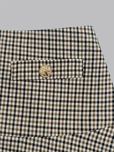 Close-up detail of a high-waisted plaid A-line skirt with vintage gold crest button