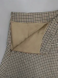 Close-up detail of a plaid A-line skirt showing soft lining and hidden side zipper.