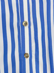 Detailed close-up of blue and white vertical striped shirt dress fabric featuring gold buttons