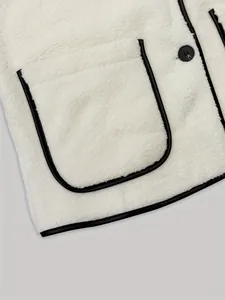 Detail showing the white sherpa fleece texture and black leather-like trim on vest