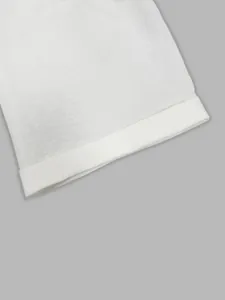 Close-up macro view of the white linen fabric and cuffed hem detail on wide-leg pants
