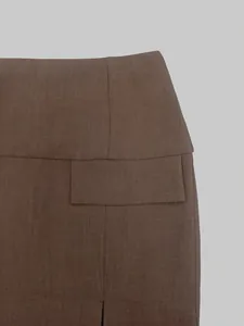 Detail view of high-waisted brown skirt showing woven fabric and flap pocket design