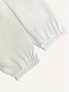 Close-up of white knit sweatpants featuring elasticated ankle cuffs and soft texture